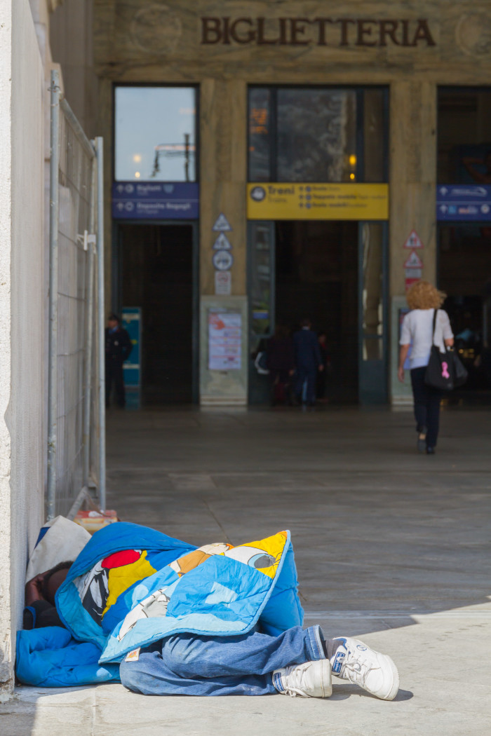 Homeless person sleeping outside Milan Train Station Italy