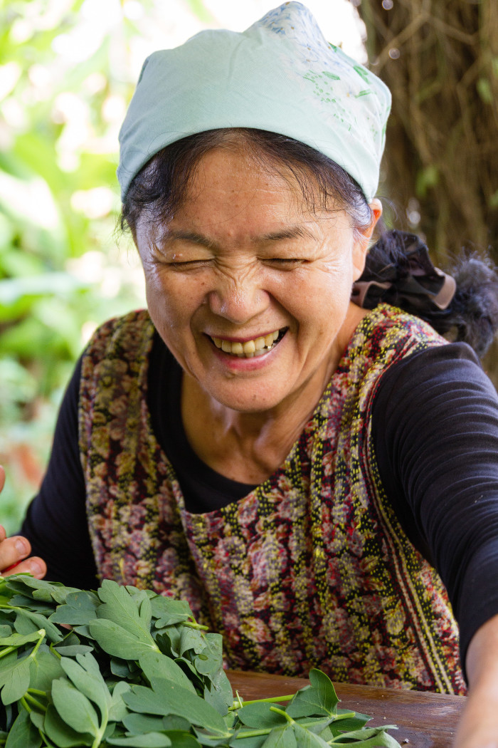 Okinawan woman laughs while picking Greens